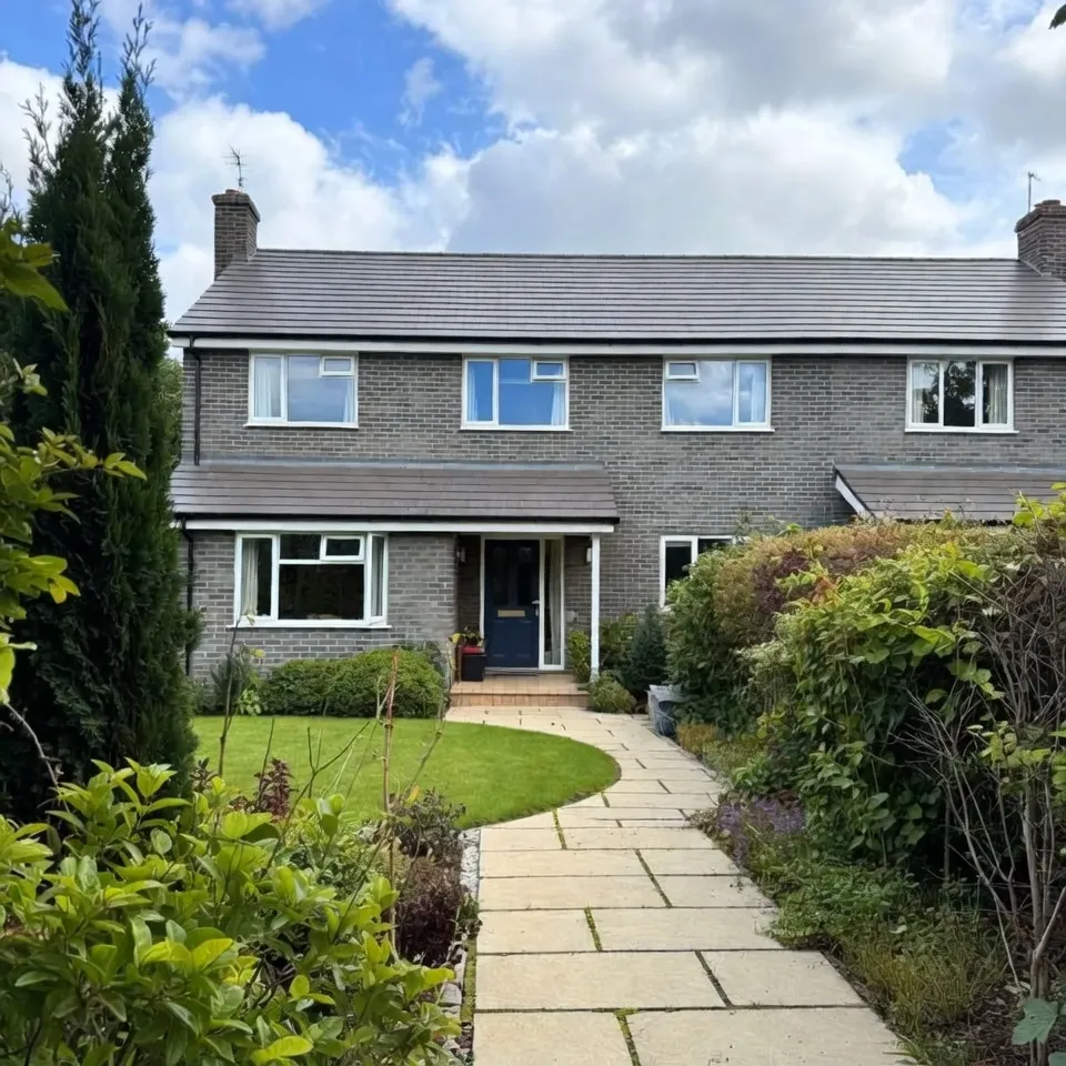 Grey brick house with white windows and blue front door.